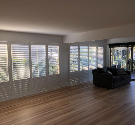 Wooden floor and white shutters — Blinds, Shutters & Awnings in Erina, NSW